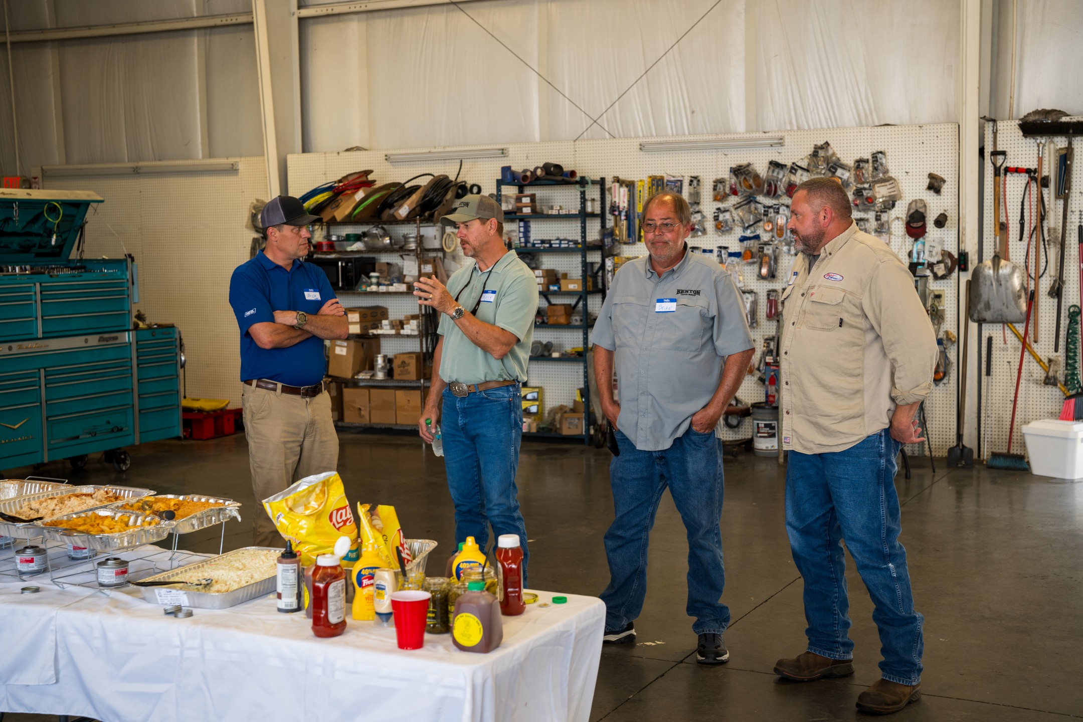 four men talking at picnic in truck repair shop