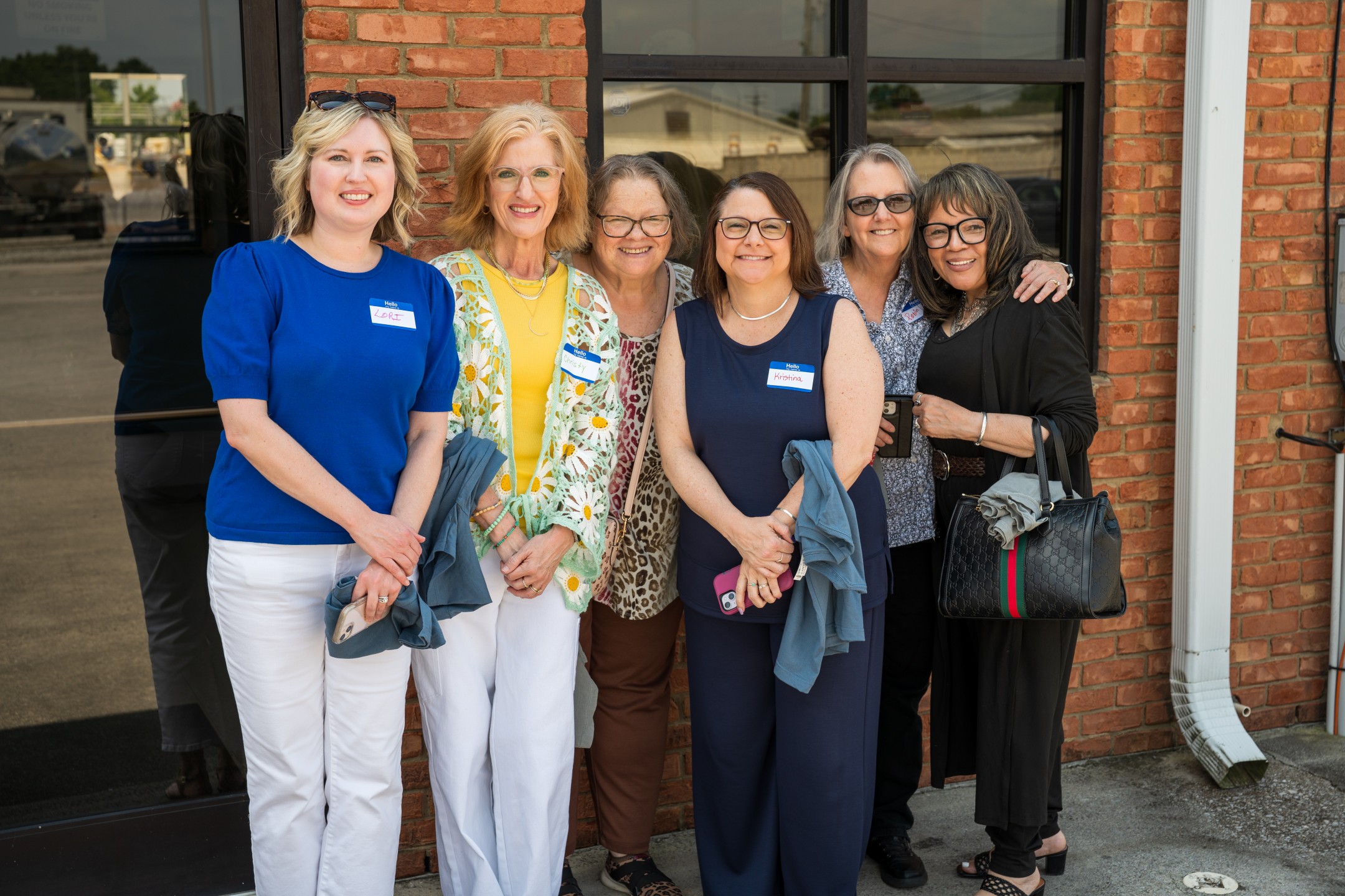 Six ladies in front of building smiling