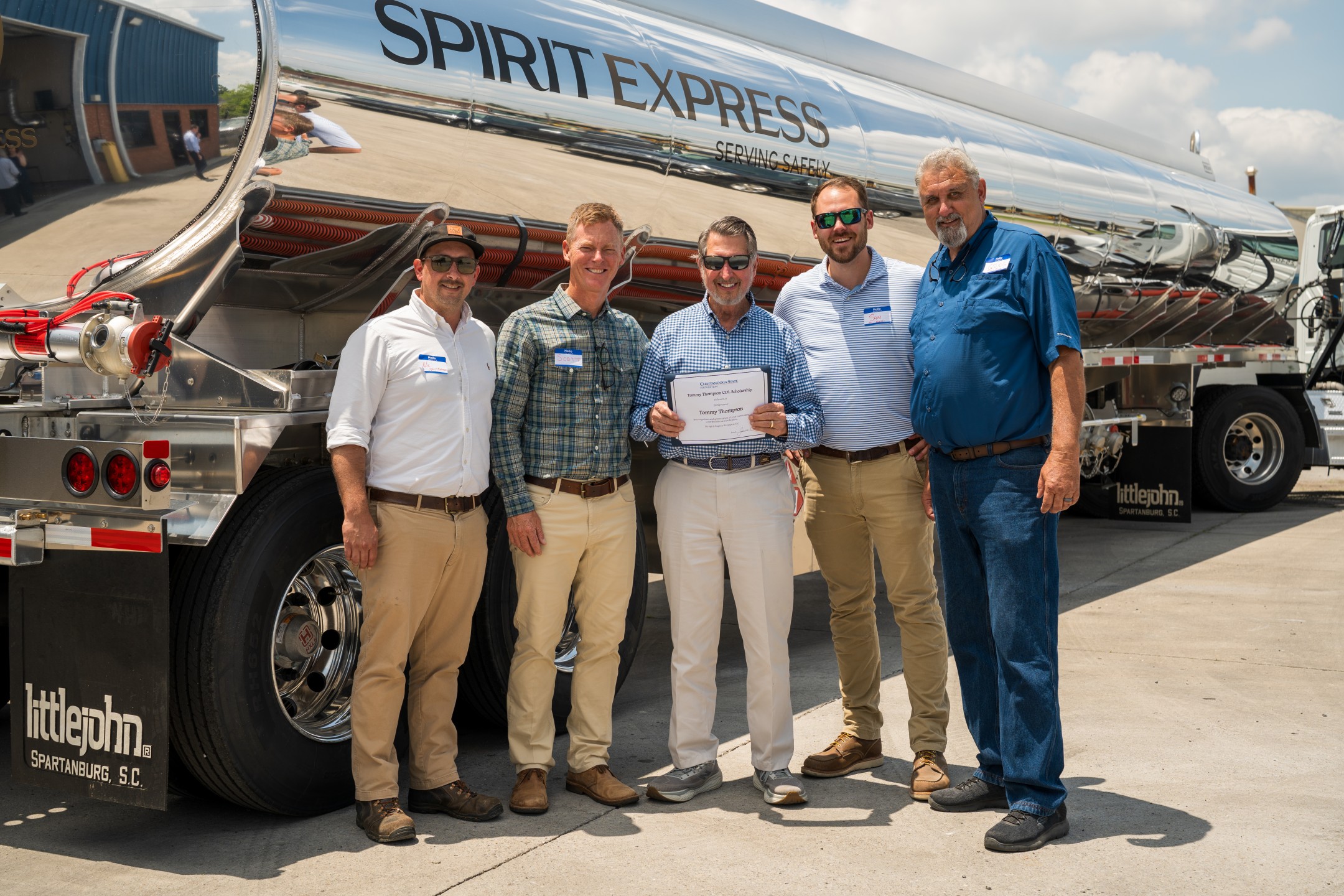 Five men in front of tanker truck with certificate in hand