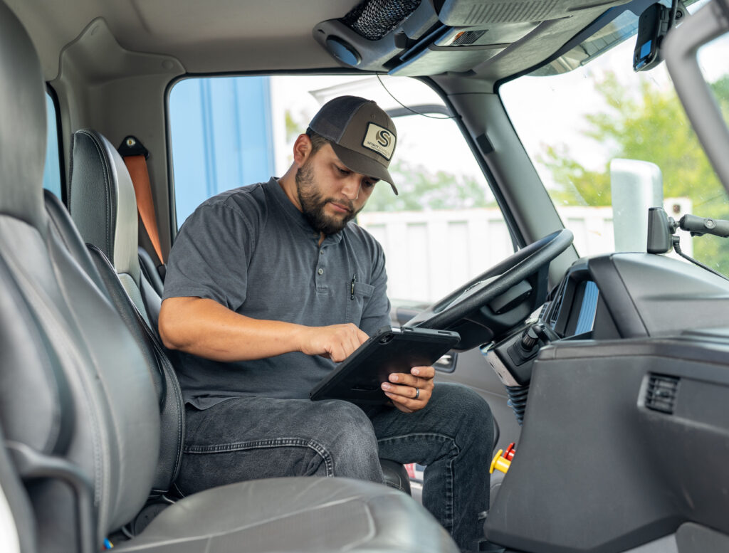 Truck driver in cab of truck with ipad