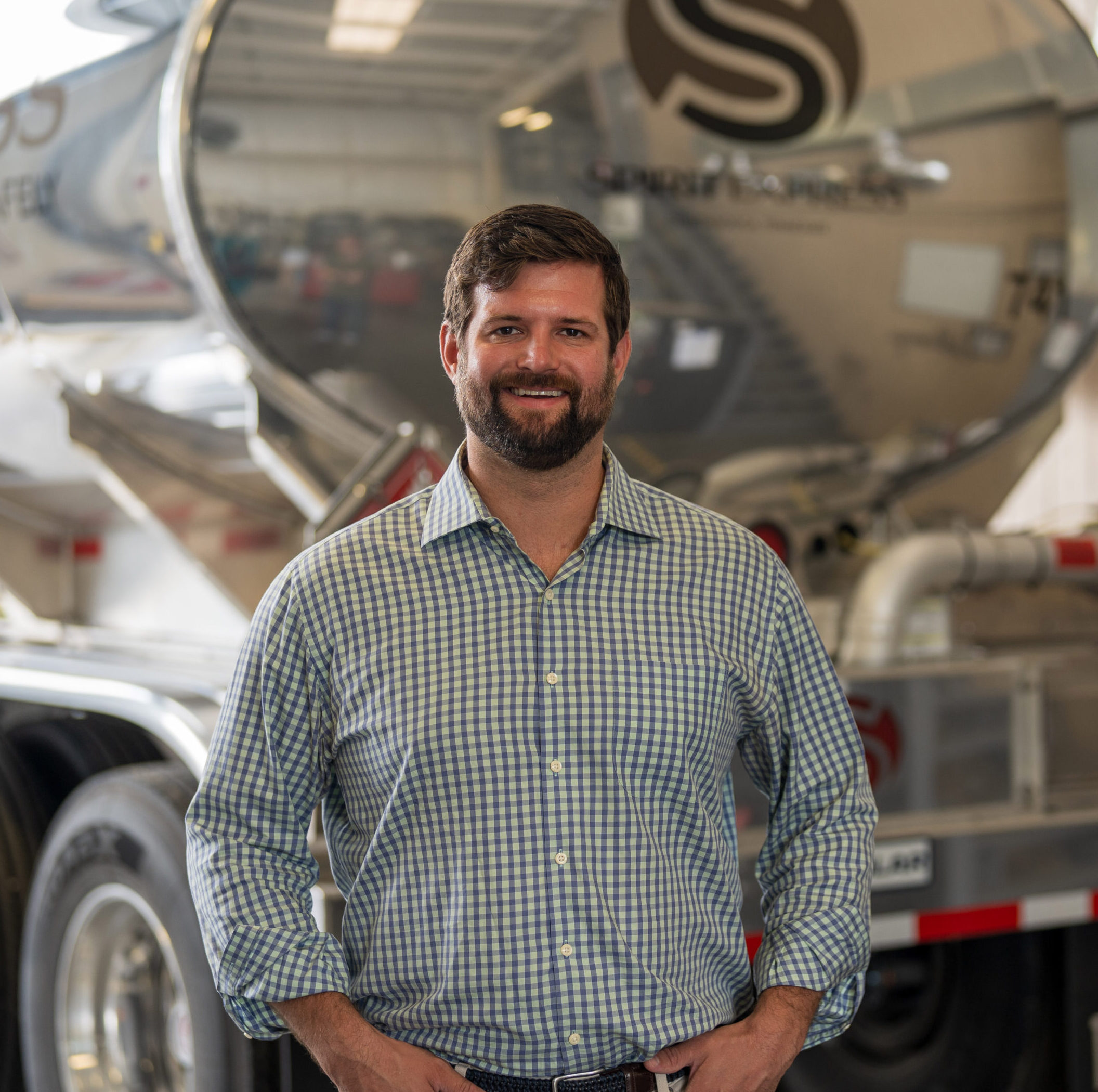 Photo of Taylor McElheney standing in front of a Spirit Express tanker truck